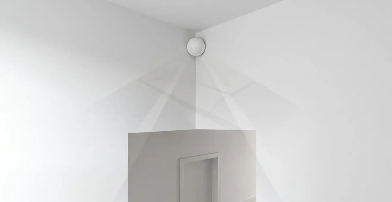 Installation d'un détecteur PIR en hauteur dans un espace intérieur minimaliste montrant l'orientation correcte et les faisceaux de détection invisibles